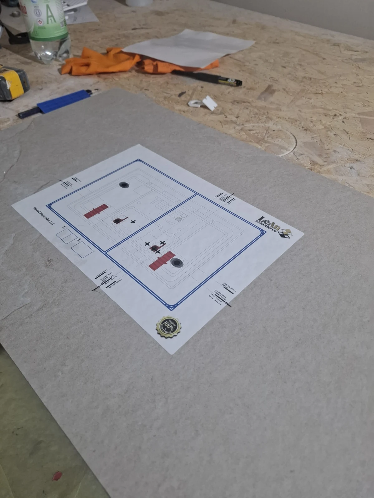 Papierowy szablon przycisku spłuczki ułożony na płytce na stole roboczym